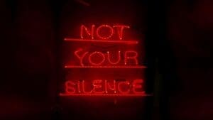 Red neon artwork reading Not Your Silence