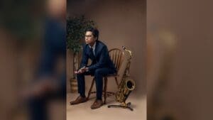 Arman Sangalang seated beside a saxophone