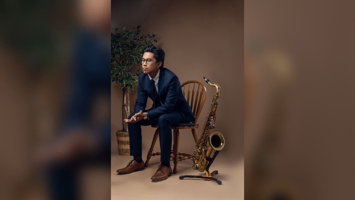 Arman Sangalang seated beside a saxophone