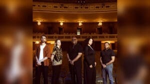 Christian McBride’s Ursa Major quintet stands in the seating area of a warmly lit theater.