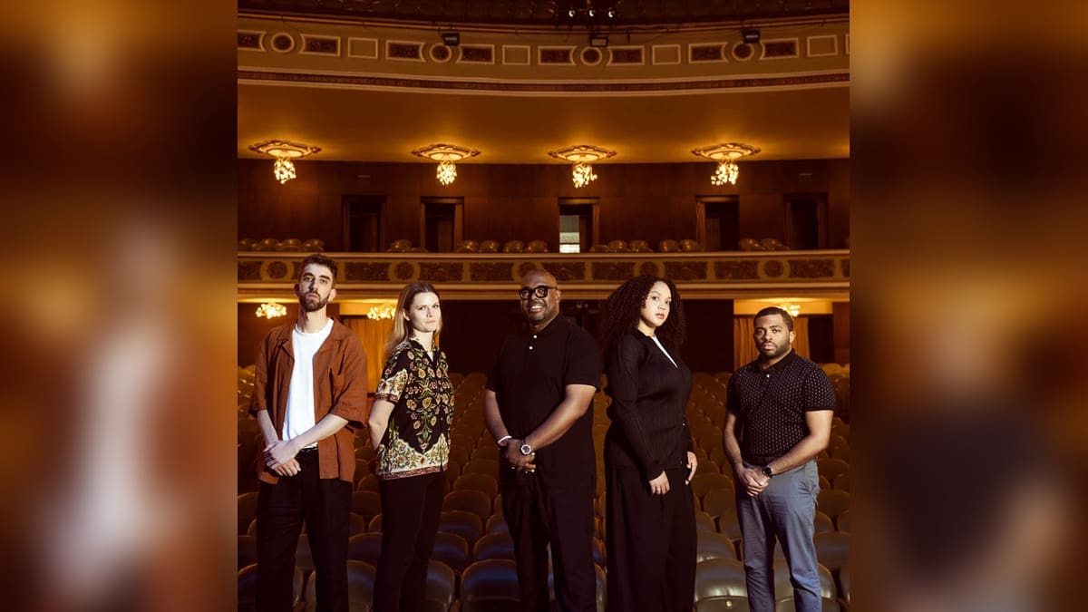 Christian McBride’s Ursa Major quintet stands in the seating area of a warmly lit theater.