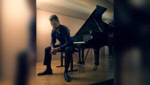 Michael Echaniz seated beside a piano
