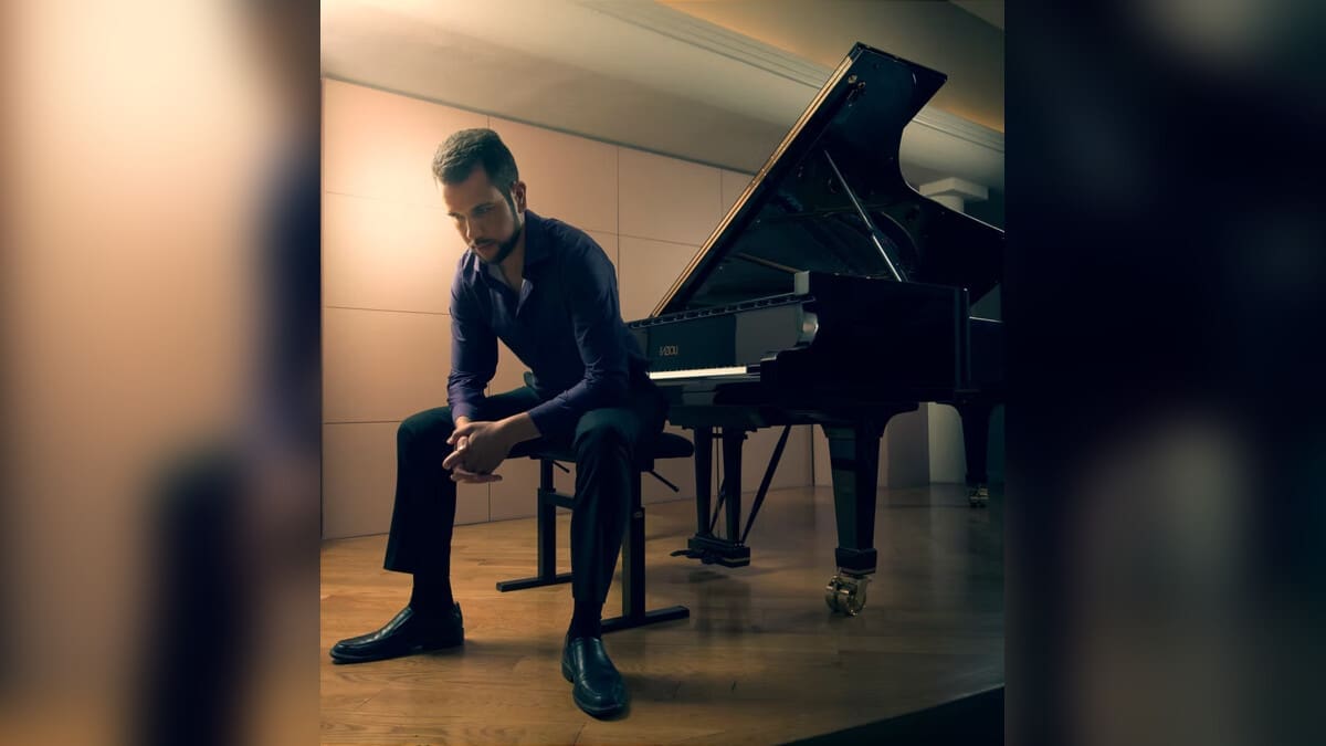 Michael Echaniz seated beside a piano
