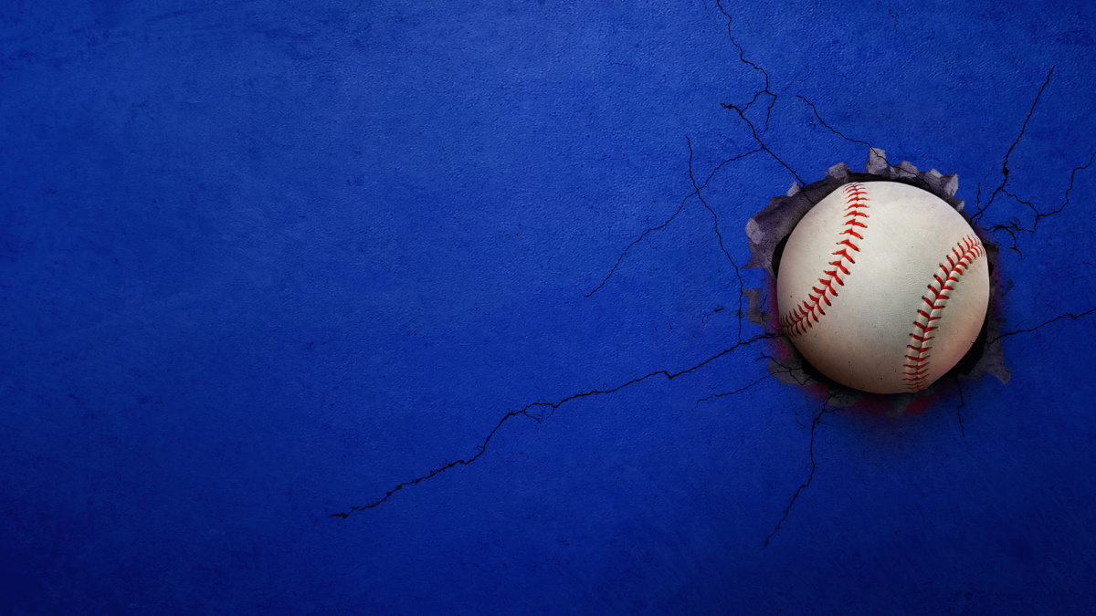 A baseball breaks through a blue wall.