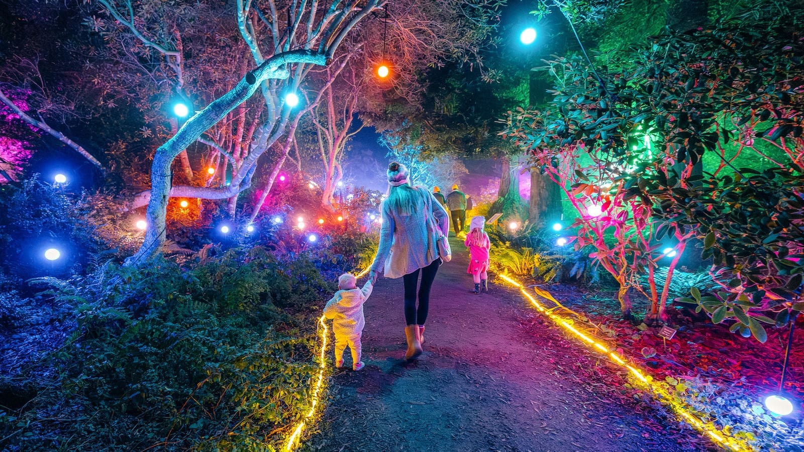 Family walks through illuminated gardens at the Festival of Lights