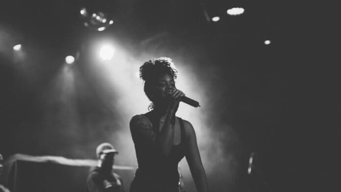 Ari Lennox performs onstage with a microphone.