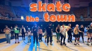 Skaters on the Henry J. Arena floor beneath Skate the Town lettering.