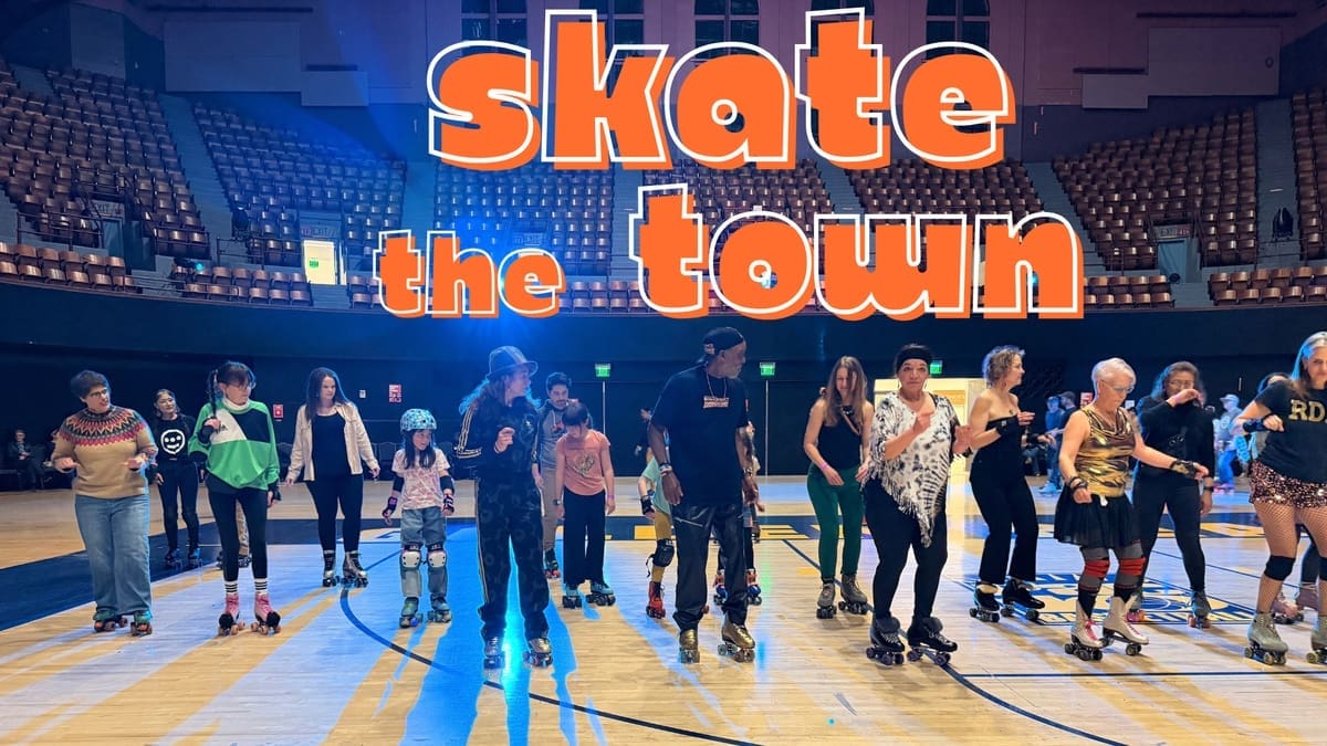 Skaters on the Henry J. Arena floor beneath Skate the Town lettering.