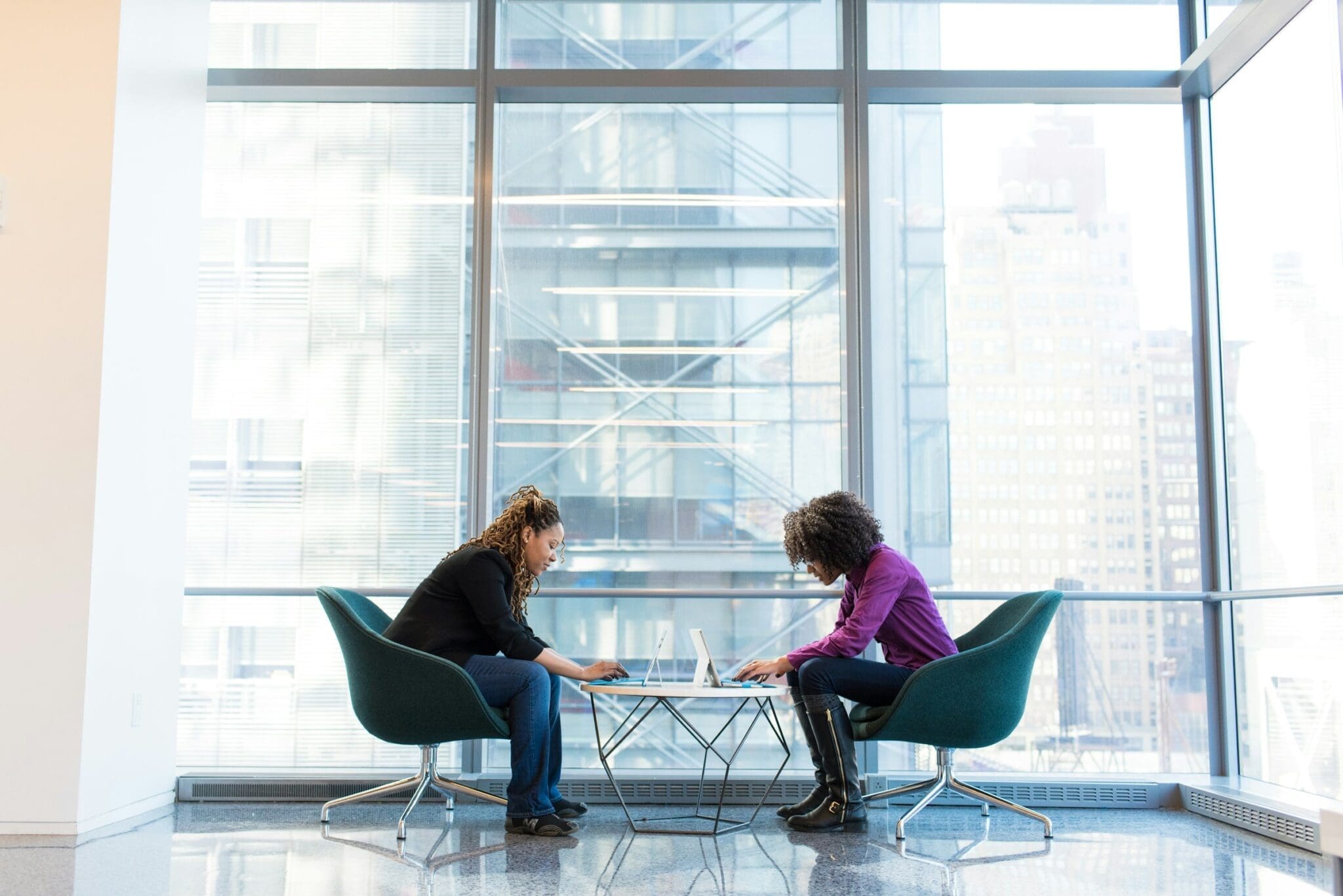 Two women collaborating with laptop computers; illustrative WOCinTechChat photograph.