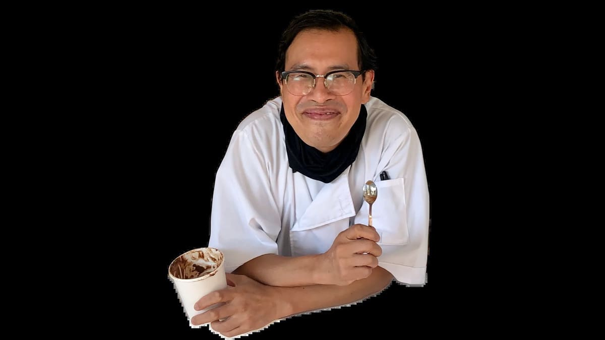 Ice cream chef Ray Lai holds a spoon and a container of ice cream.