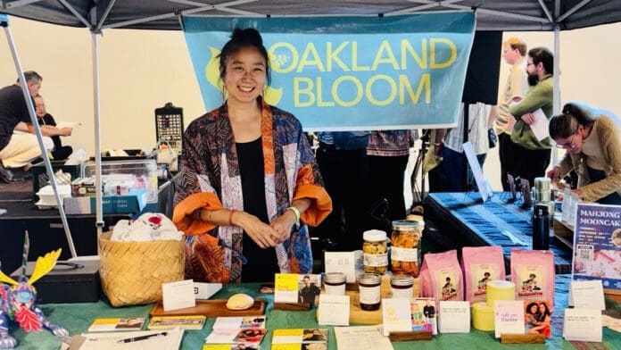 A vendor at the Oakland Bloom marketplace at The Edible Atlas, with packaged products displayed on the table.